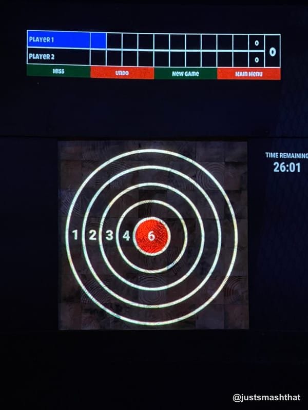 Digital scoreboard and bullseye target projected onto an axe throwing board at Just Smash That